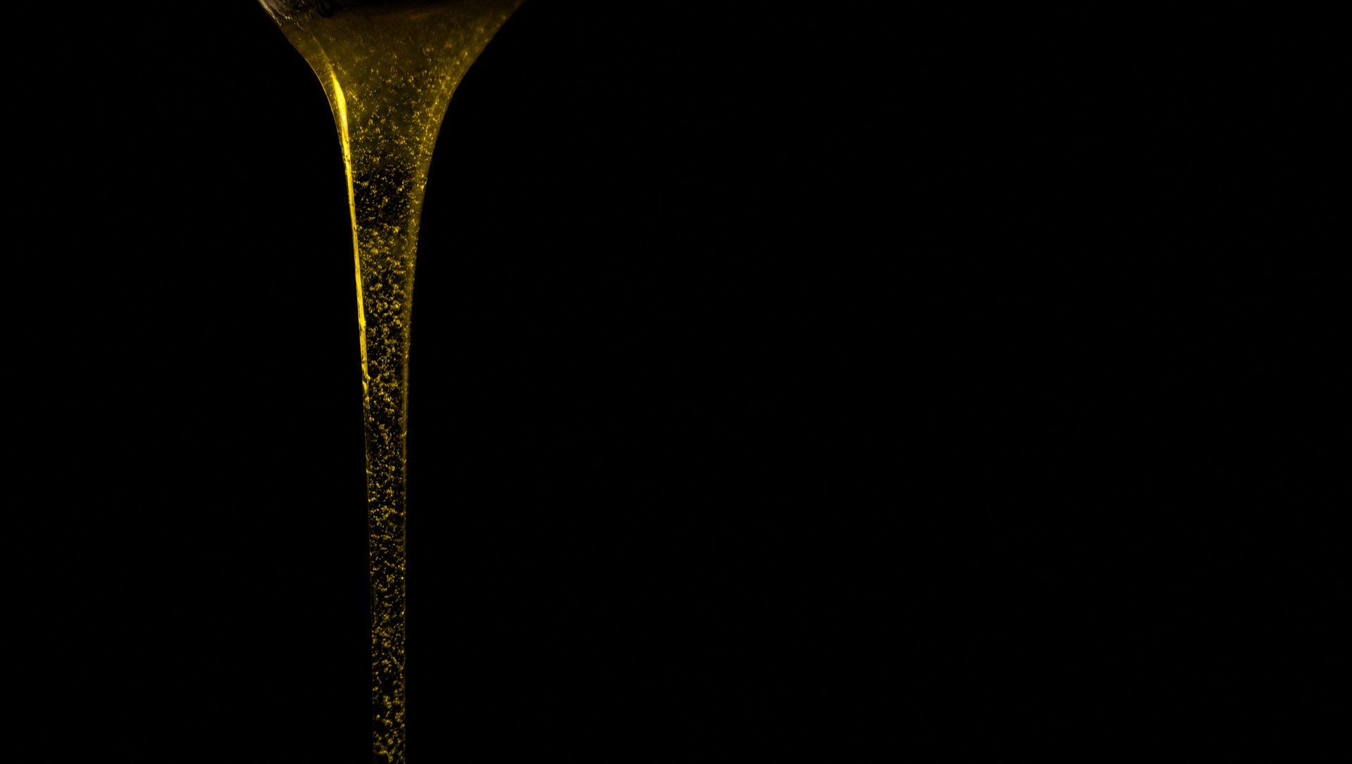 Green gold olive oil pouring in bright sunlight